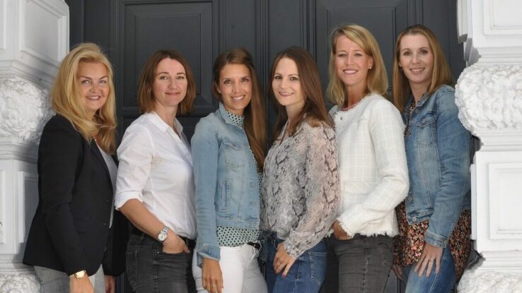 Fotografie von sechs Frauen vor einer Tür.