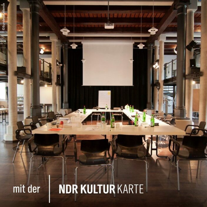Bundesakademie Wolfenbüttel © Bundesakademie Ansicht eines Konferenzraums, über den Konferenztisch hinweg Richtung Leinwand. Schrift: "Mit der NDR Kultur Karte"